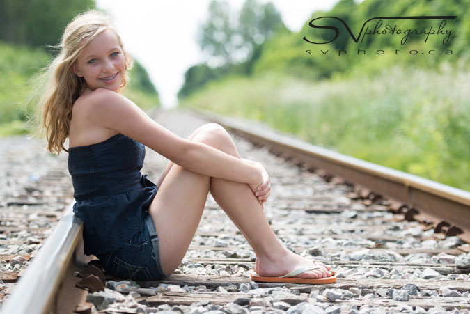 portrait of a teen sitting on the railway tracks