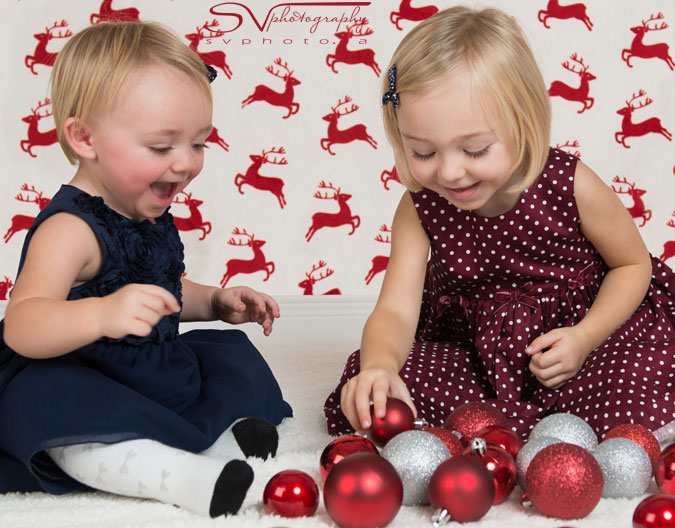 cute sisters playing with christmas ornaments
