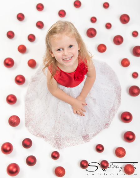 little girl surrounded by red ornaments
