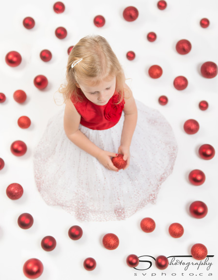 portrait of a little girl surrounded by red ornaments