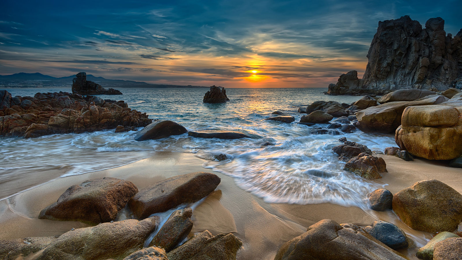 waves rush past rocks during sunrise landscape photography
