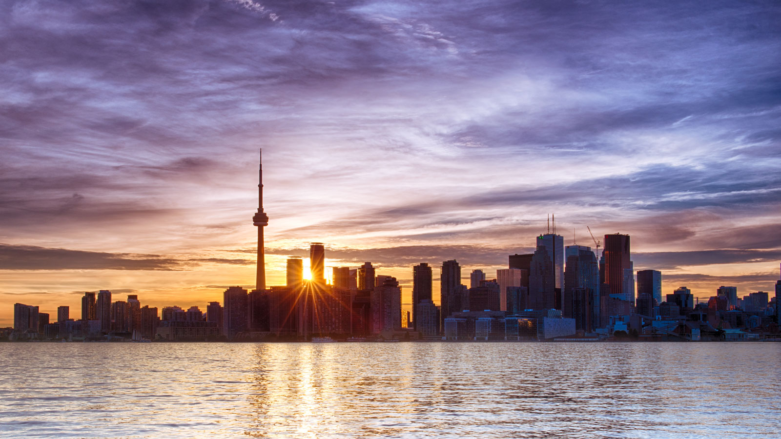 The sun sets behind the distinctive skyline of Toronto cityscape landscape photography